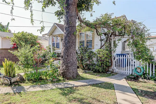 a view of a house with a small yard and large tree