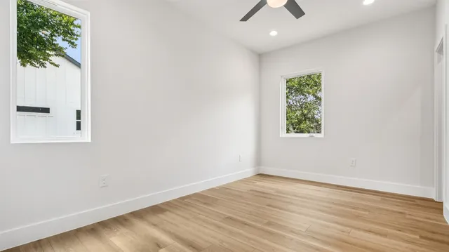 an empty room with wooden floor & windows