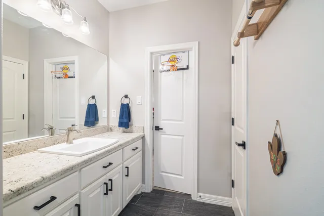 a bathroom with a granite countertop sink a mirror and shower