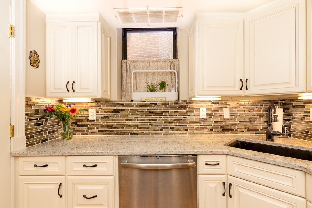 a sink with granite countertop white cabinets and a window