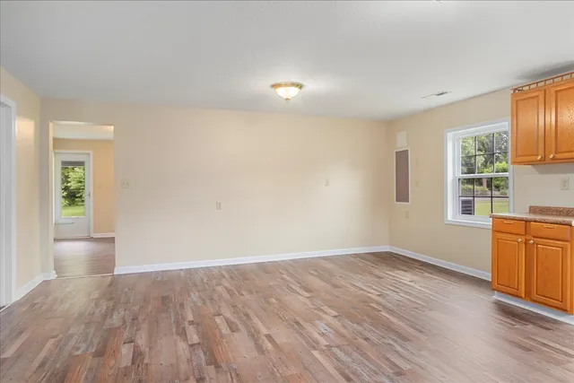 an empty room with wooden floor and windows