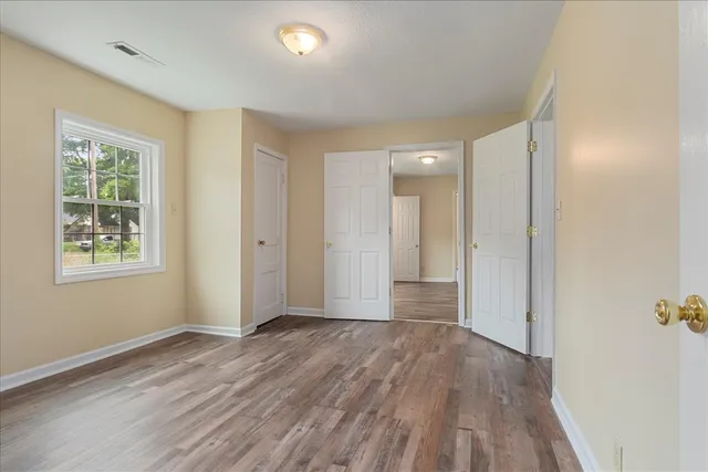 a view of an empty room with wooden floor and a window