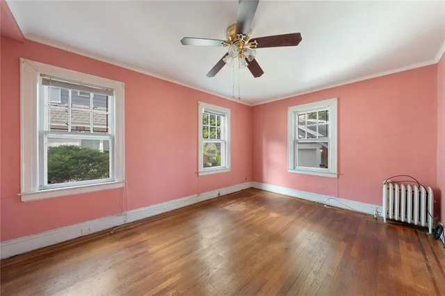 a view of an empty room with a window and wooden floor