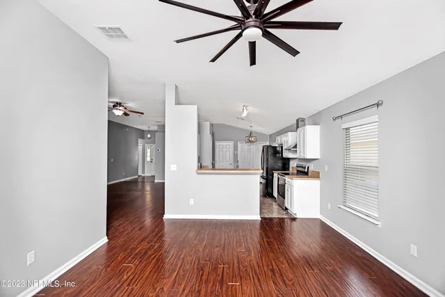 a view of a kitchen with a fridge a ceiling fan and wooden floor