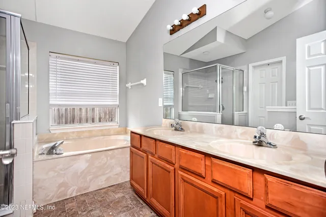 a bathroom with a granite countertop sink mirror bathtub and next to a window