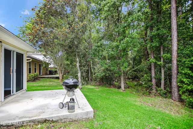 a patio with table and chairs and a yard