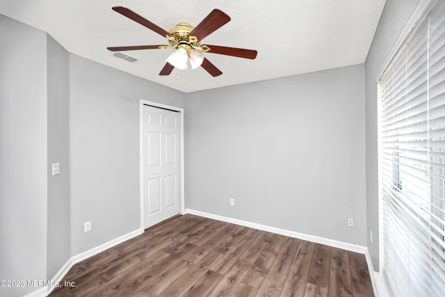 an empty room with wooden floor and windows