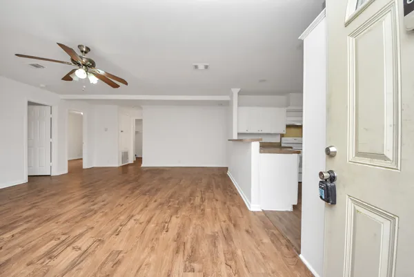 a view of empty room with wooden floor and fan