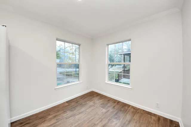 an empty room with wooden floor and windows
