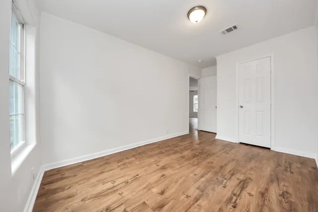 an empty room with wooden floor and windows