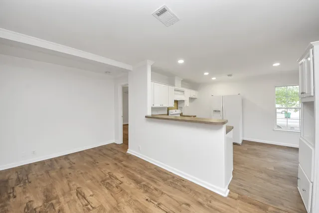 a open kitchen with white cabinets and wooden floor