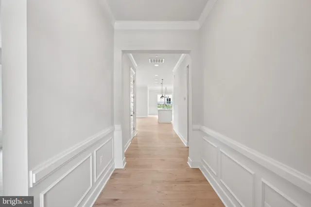 a view of a hallway with wooden floor and a bathroom