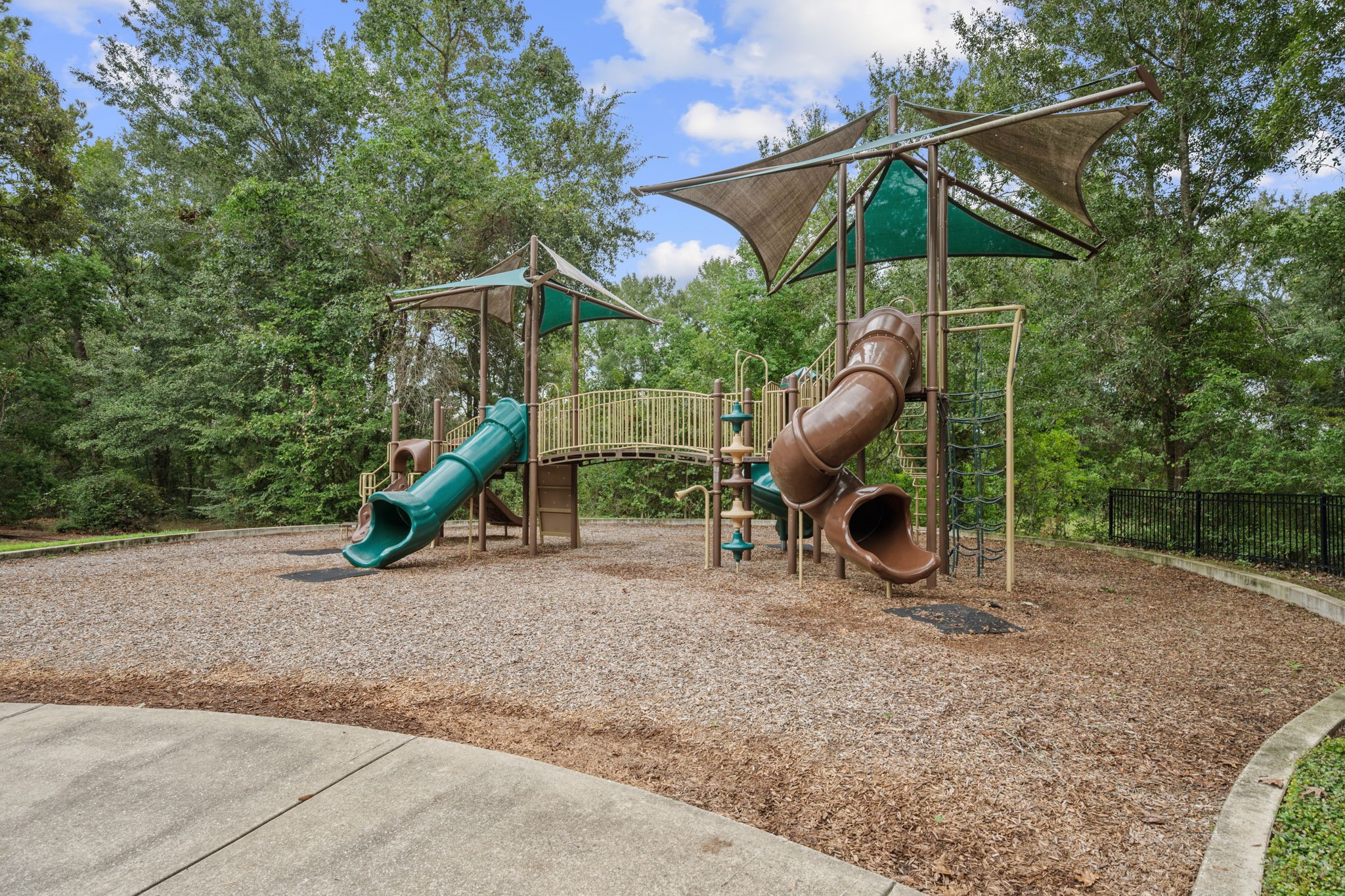 3043 Marble Rise Trail Porter, TX 77365 - Photo 24 of 27 Charming playground set amidst lush greenery, featuring slides and climbing structures perfect for family fun and outdoor activities.