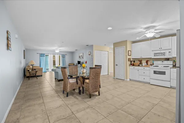a dining area with stainless steel appliances kitchen island granite countertop a dining table chairs and a refrigerator