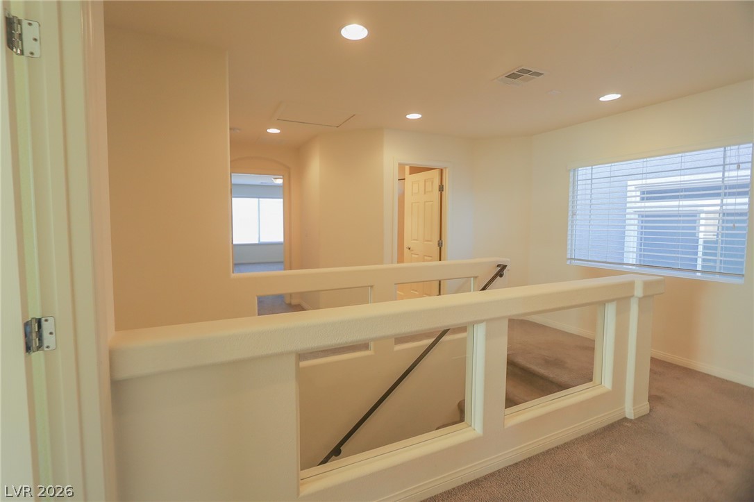 6418 Jackson Spring Road Las Vegas, NV 89118 - Photo 13 of 20 A well-lit landing and staircase beckon, featuring recessed lighting and carpeted floors leading to additional rooms.