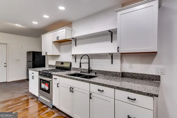 a kitchen with stainless steel appliances granite countertop a sink stove and cabinets