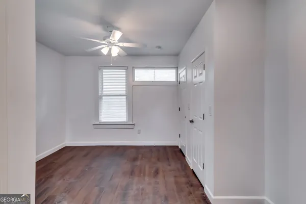 a view of an empty room with wooden floor and a window