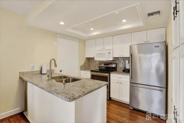 a kitchen with stainless steel appliances granite countertop a refrigerator a sink dishwasher a stove with wooden floors