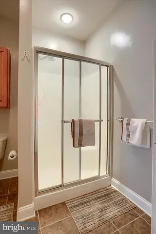 a view of an empty room with wooden floor and a bathroom