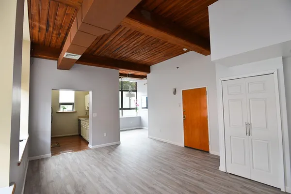a view of an empty room with wooden floor and a window