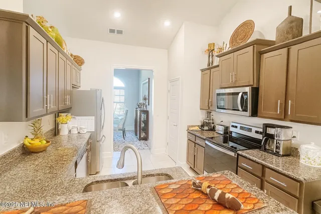 a kitchen with stainless steel appliances granite countertop a sink and a refrigerator