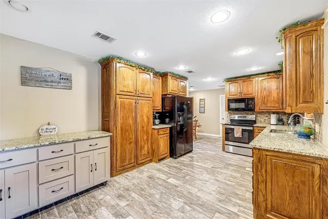 a kitchen with granite countertop a refrigerator stove top oven and sink