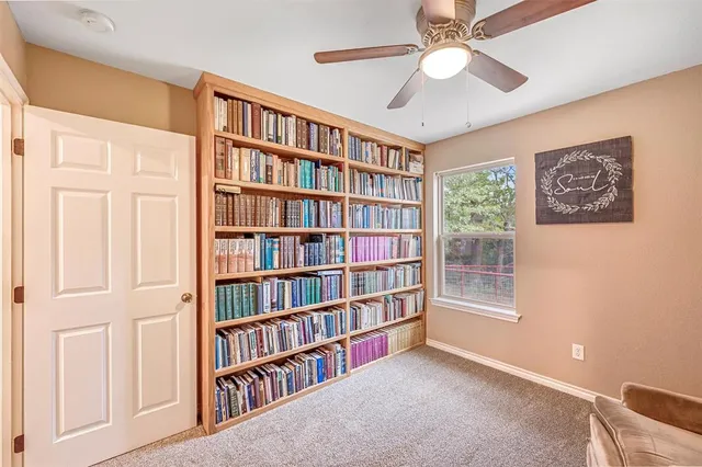 a view of an empty room with bookshelf and a window