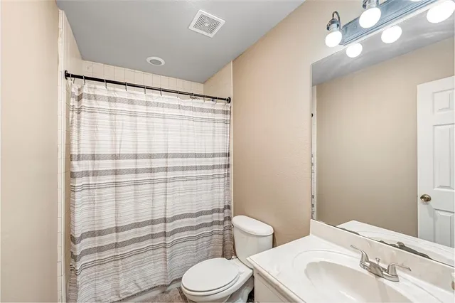 a bathroom with a sink a toilet a mirror and shower curtain
