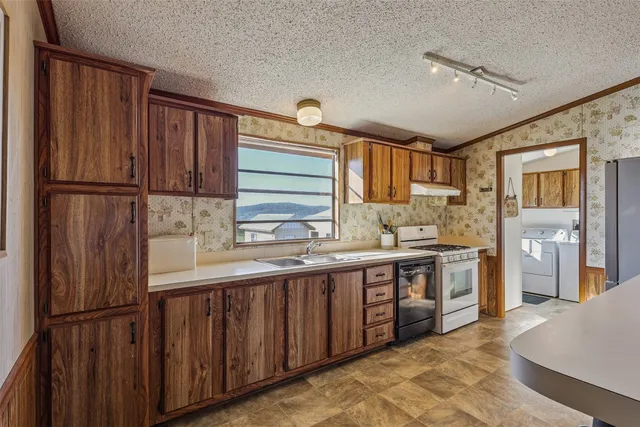 a kitchen with stainless steel appliances granite countertop a refrigerator a sink dishwasher and wooden cabinets with wooden floor