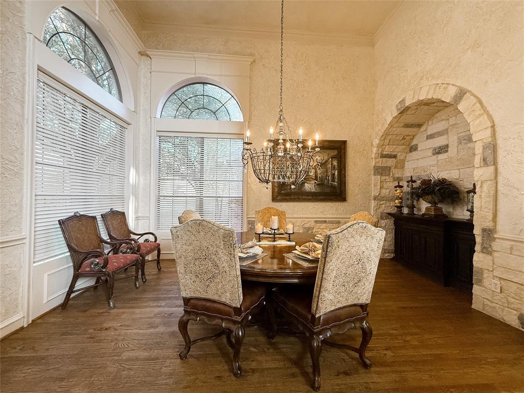 1919 Kings Pass Heath, TX 75032 - Photo 14 of 38 Dining area with hanging lights, a textured wall, dark wood-style flooring, arched walkways, and crown molding