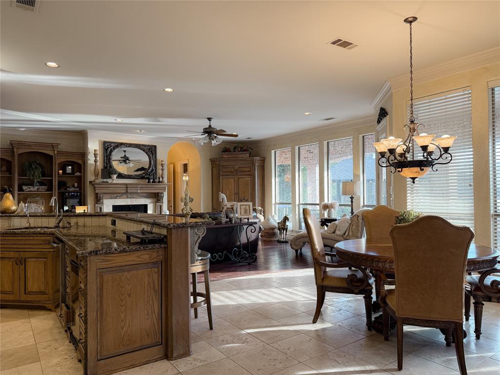 1919 Kings Pass Heath, TX 75032 - Photo 18 of 38 Dining space with a fireplace, a chandelier, a ceiling fan, ornamental molding, and arched walkways
