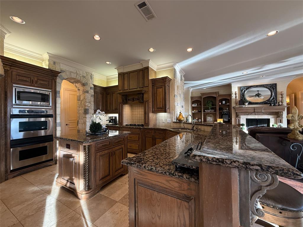 1919 Kings Pass Heath, TX 75032 - Photo 19 of 38 Kitchen with arched walkways, crown molding, stainless steel appliances, dark stone counters, and a peninsula