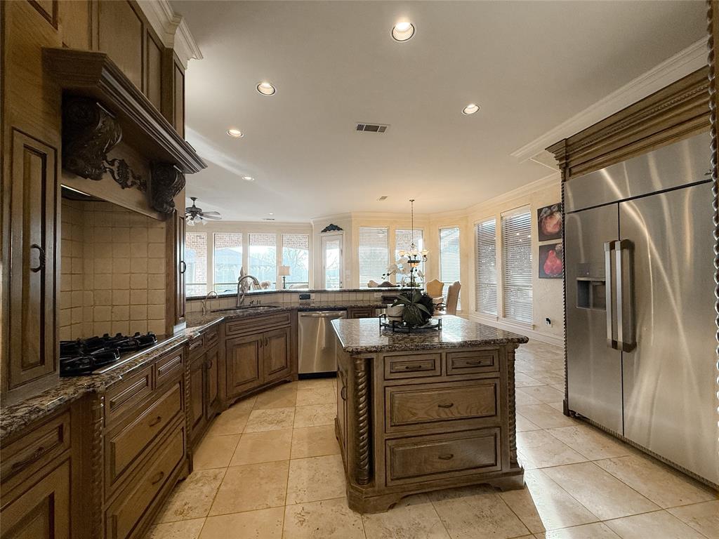 1919 Kings Pass Heath, TX 75032 - Photo 20 of 38 Kitchen featuring stainless steel appliances, dark stone countertops, crown molding, hanging light fixtures, and a kitchen island