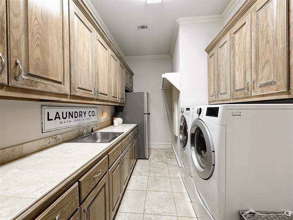 1919 Kings Pass Heath, TX 75032 - Photo 30 of 38 Laundry area featuring cabinet space, crown molding, light tile patterned floors, and washer and dryer