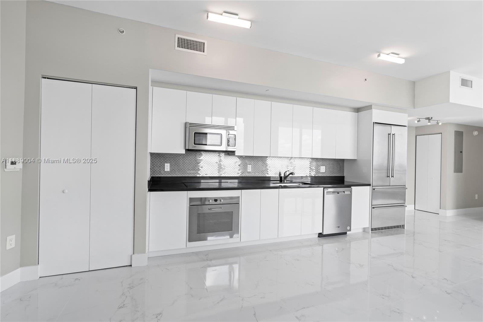 92 Southwest 3rd Street, Unit 5206 Miami, FL 33130 - Photo 4 of 21 a kitchen with white cabinets and stainless steel appliances