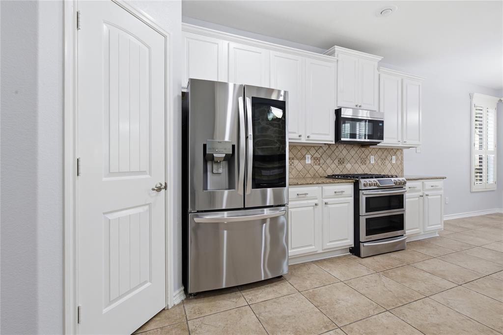 10001 Thurman Road Fort Worth, TX 76244 - Photo 13 of 40 Kitchen featuring stainless steel appliances, white cabinetry, a decorative tile backsplash, light-toned tile flooring, and a pantry door