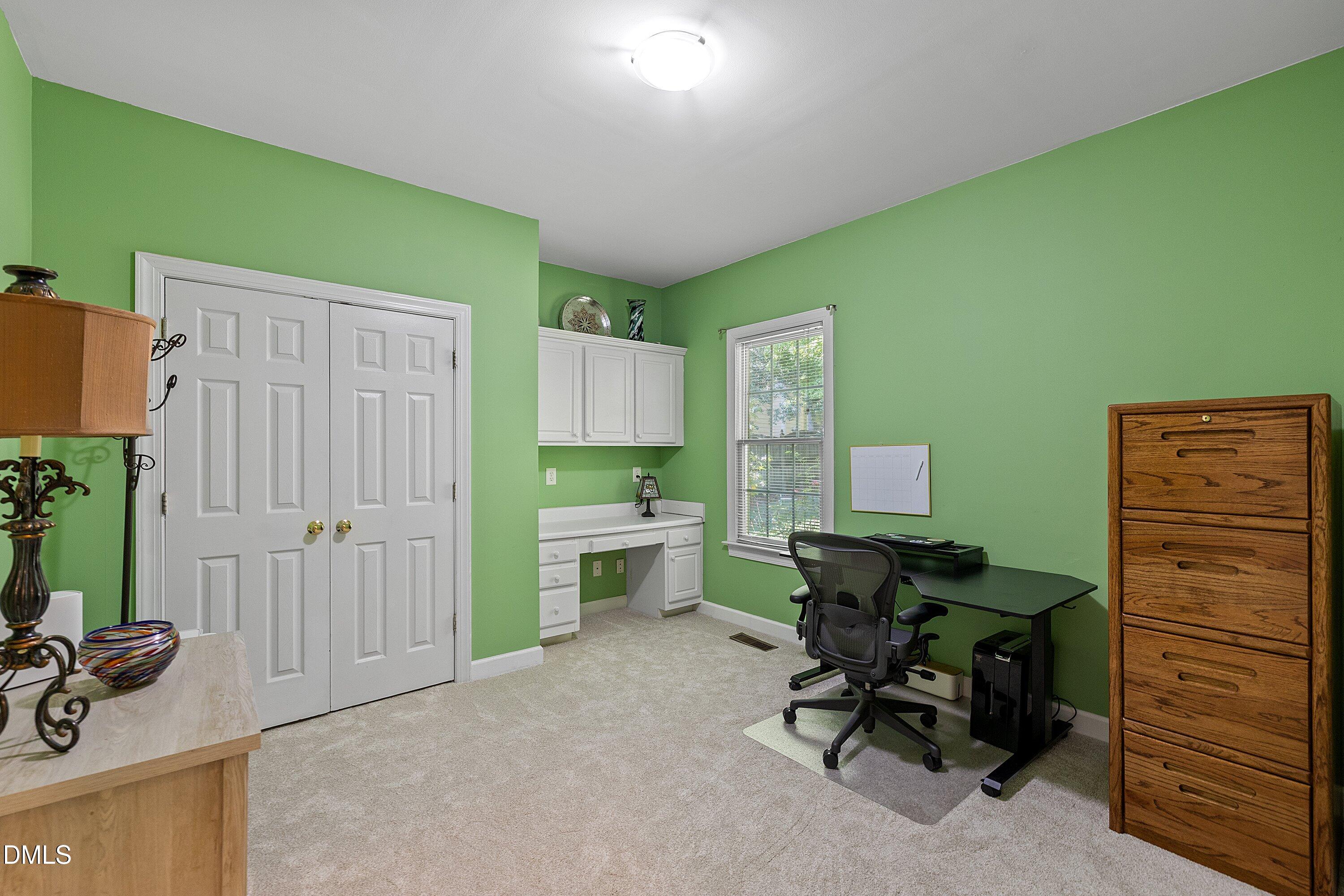 3914 Sterling Ridge Lane Durham, NC 27707 - Photo 28 of 66 Built-in desk with overhead cabinetry, window providing natural light, and paneled closet doors