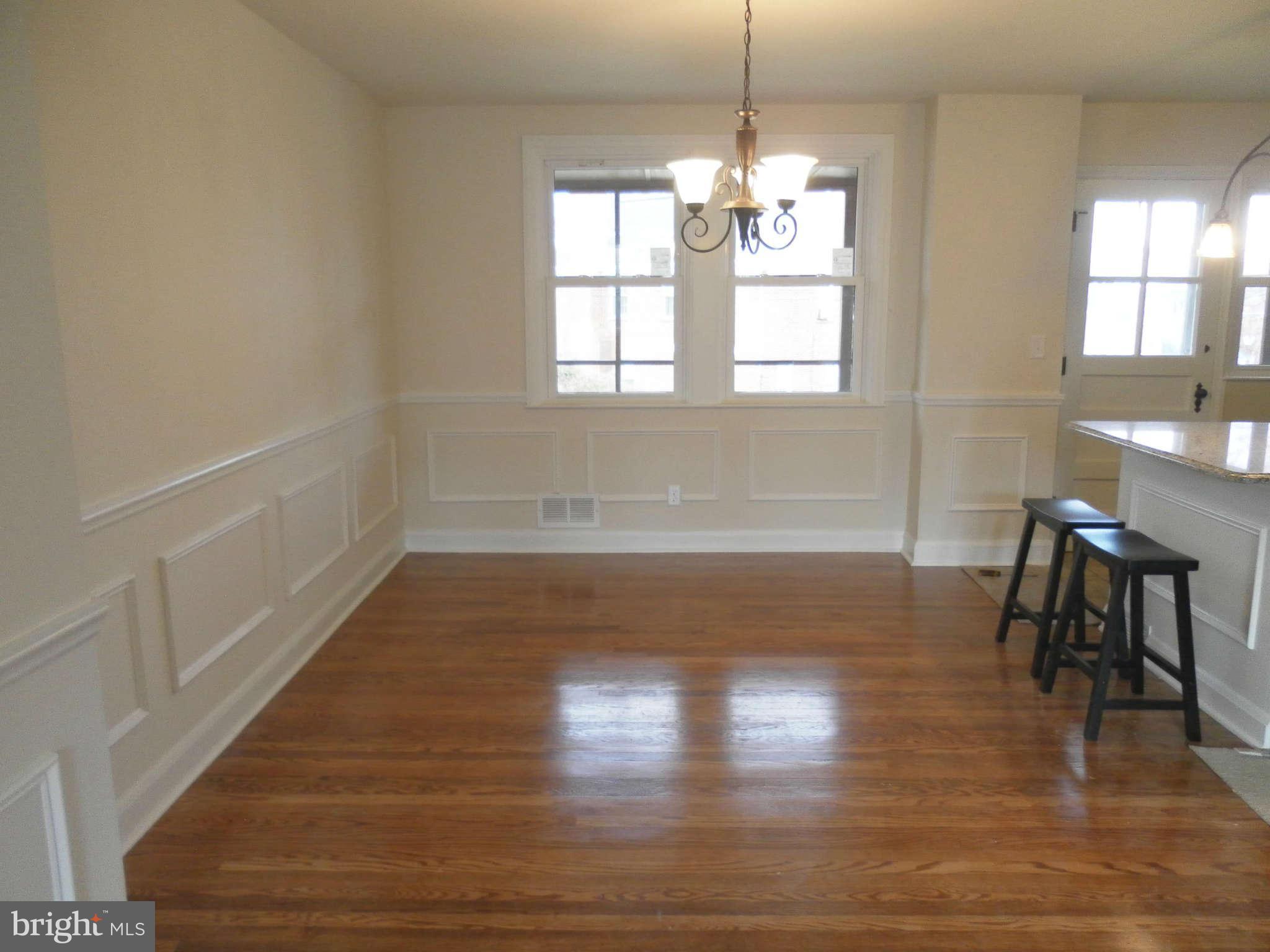 1007 Harwall Road Baltimore, MD 21207 - Photo 8 of 16 a room with wooden floor a chandelier a glass table and windows