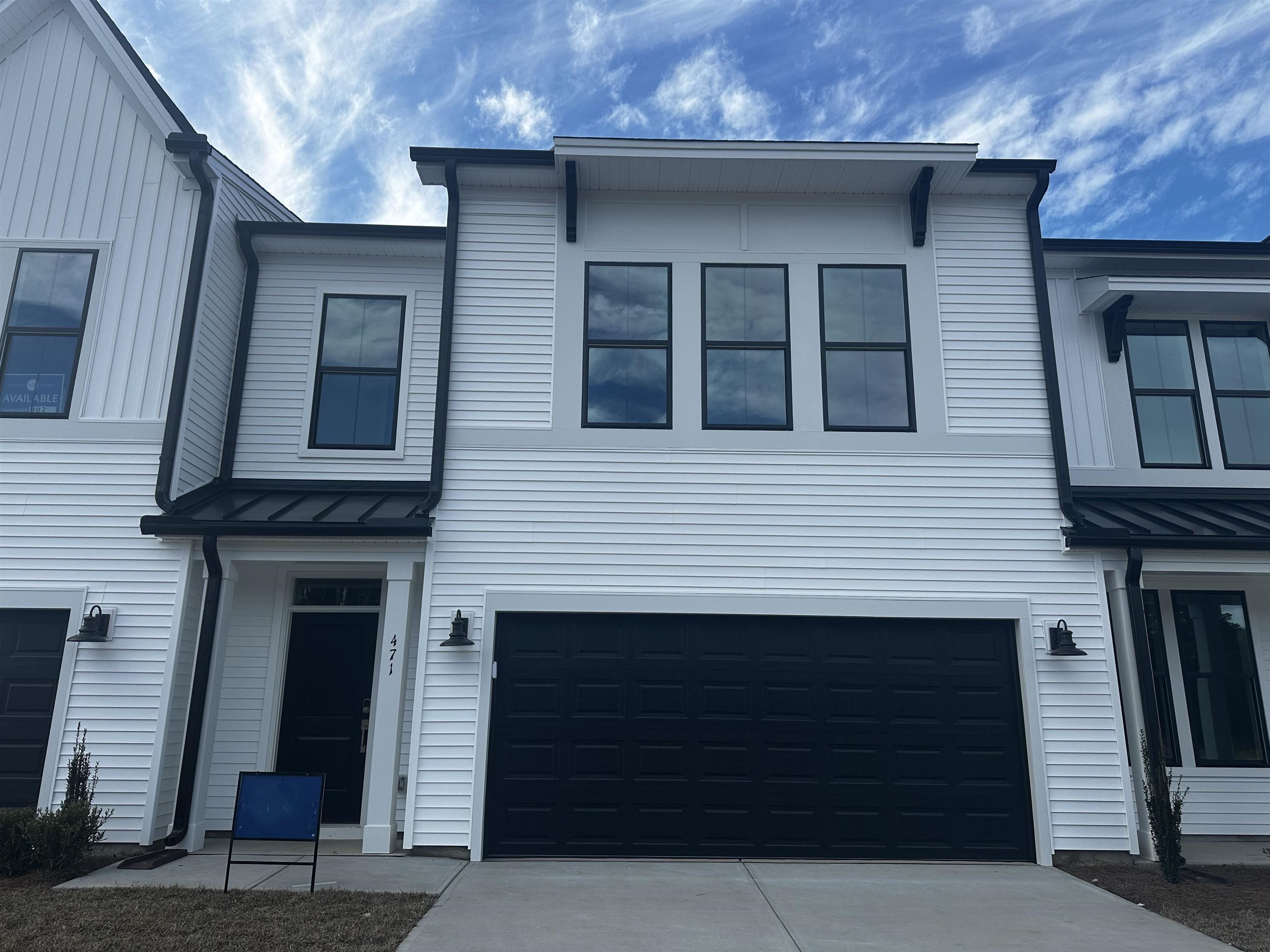 View of front of house featuring a metal roof, a standing seam roof, an attached garage, and driveway