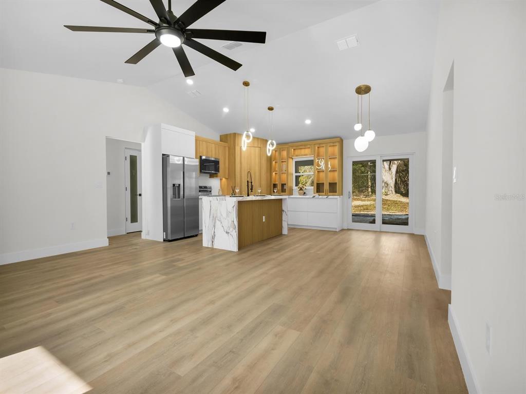 11790 Orange Road Ocklawaha, FL 32179 - Photo 4 of 21 a view of a living room a kitchen and a chandelier fan