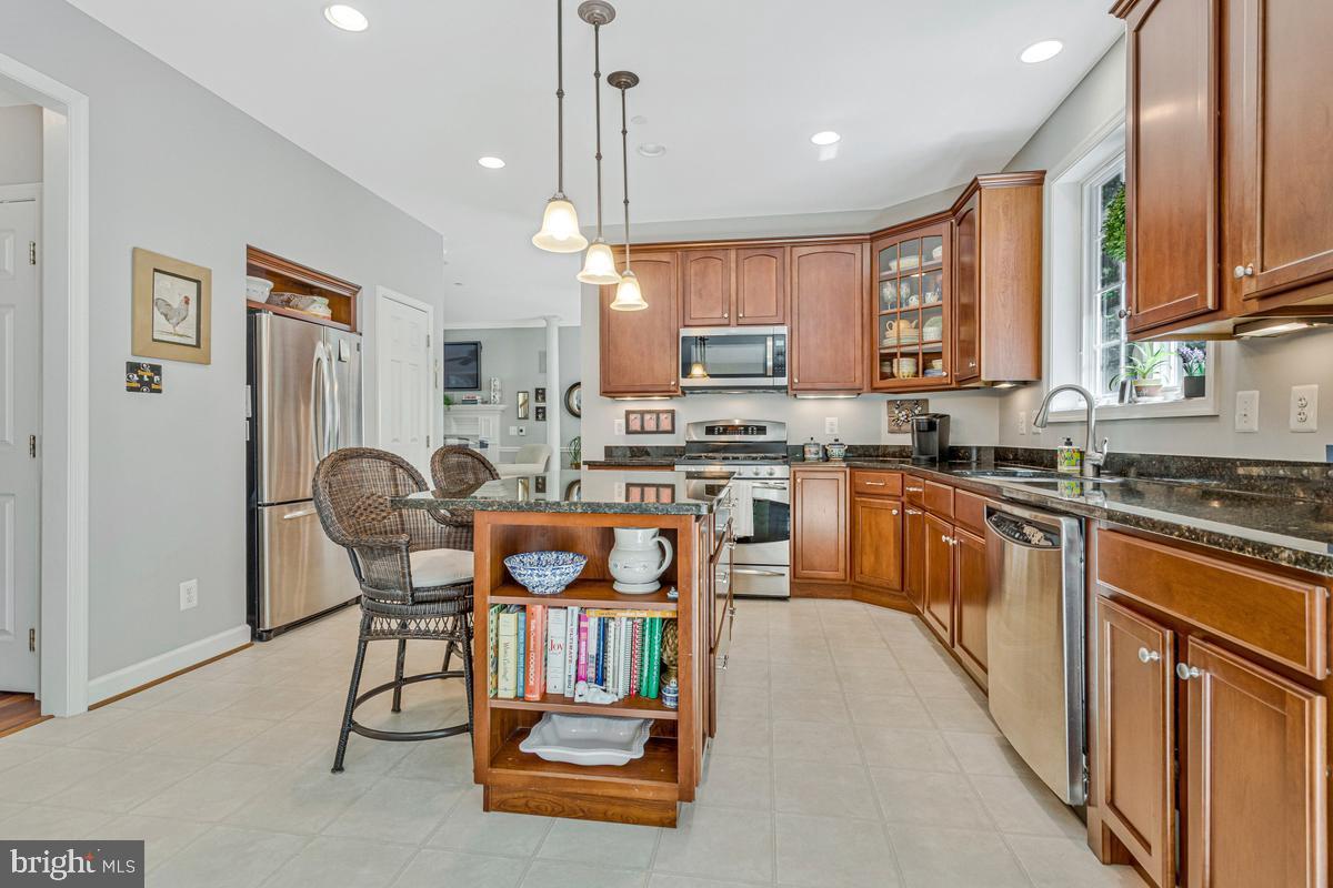 11565 Magnolia Court Issue, MD 20645 - Photo 16 of 68 a kitchen with stainless steel appliances granite countertop a stove top oven a refrigerator a sink dishwasher a dining table and chairs with wooden floor
