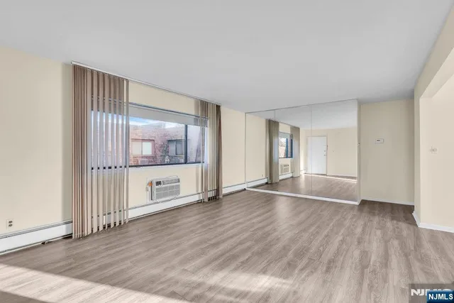 a view of an empty room with wooden floor and fan