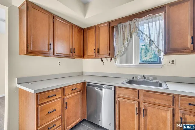 a kitchen with stainless steel appliances granite countertop white cabinets a sink and a large window