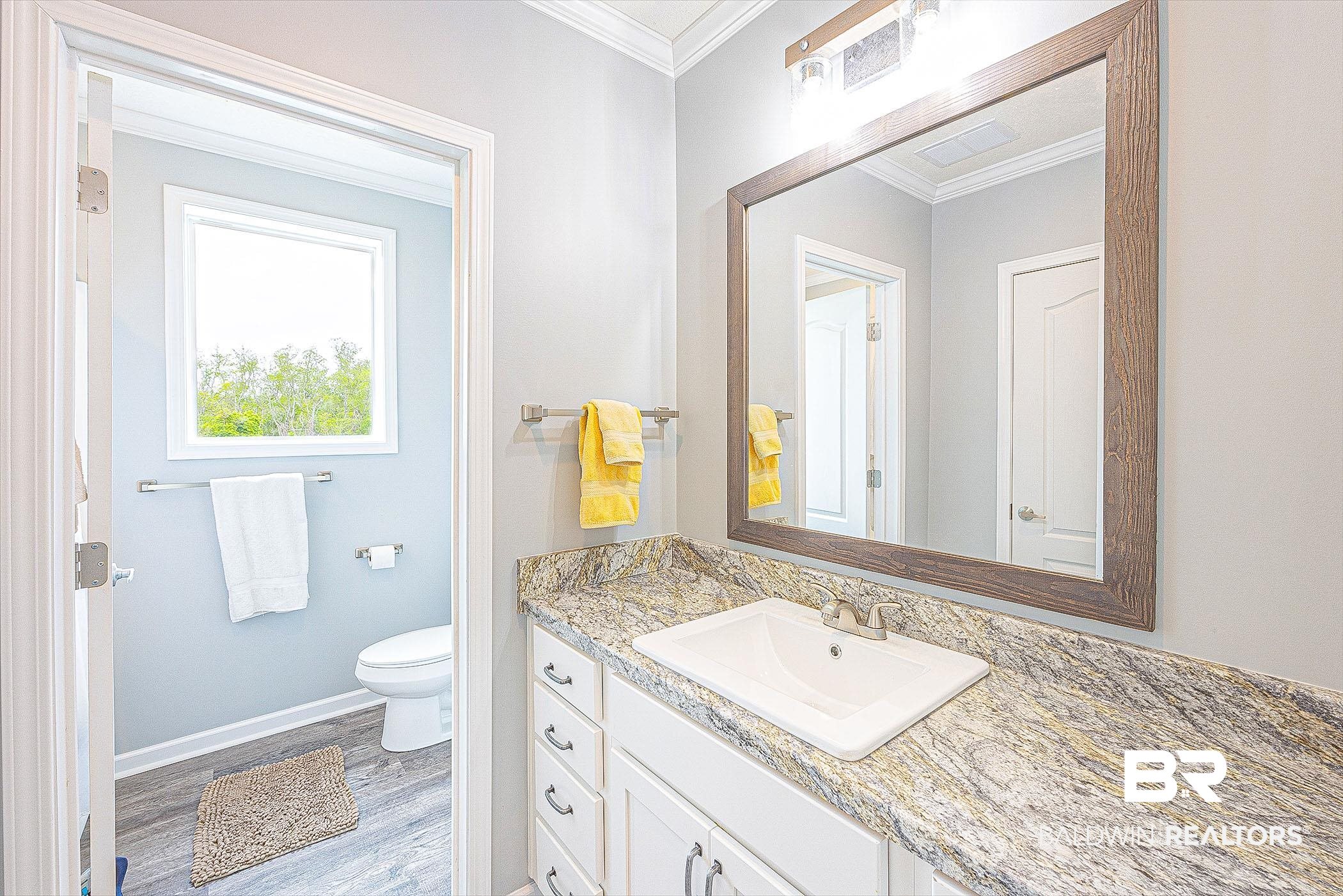 16000 John Bauer Road Summerdale, AL 36580 - Photo 27 of 34 Bathroom featuring baseboards, toilet, wood finished floors, crown molding, and vanity