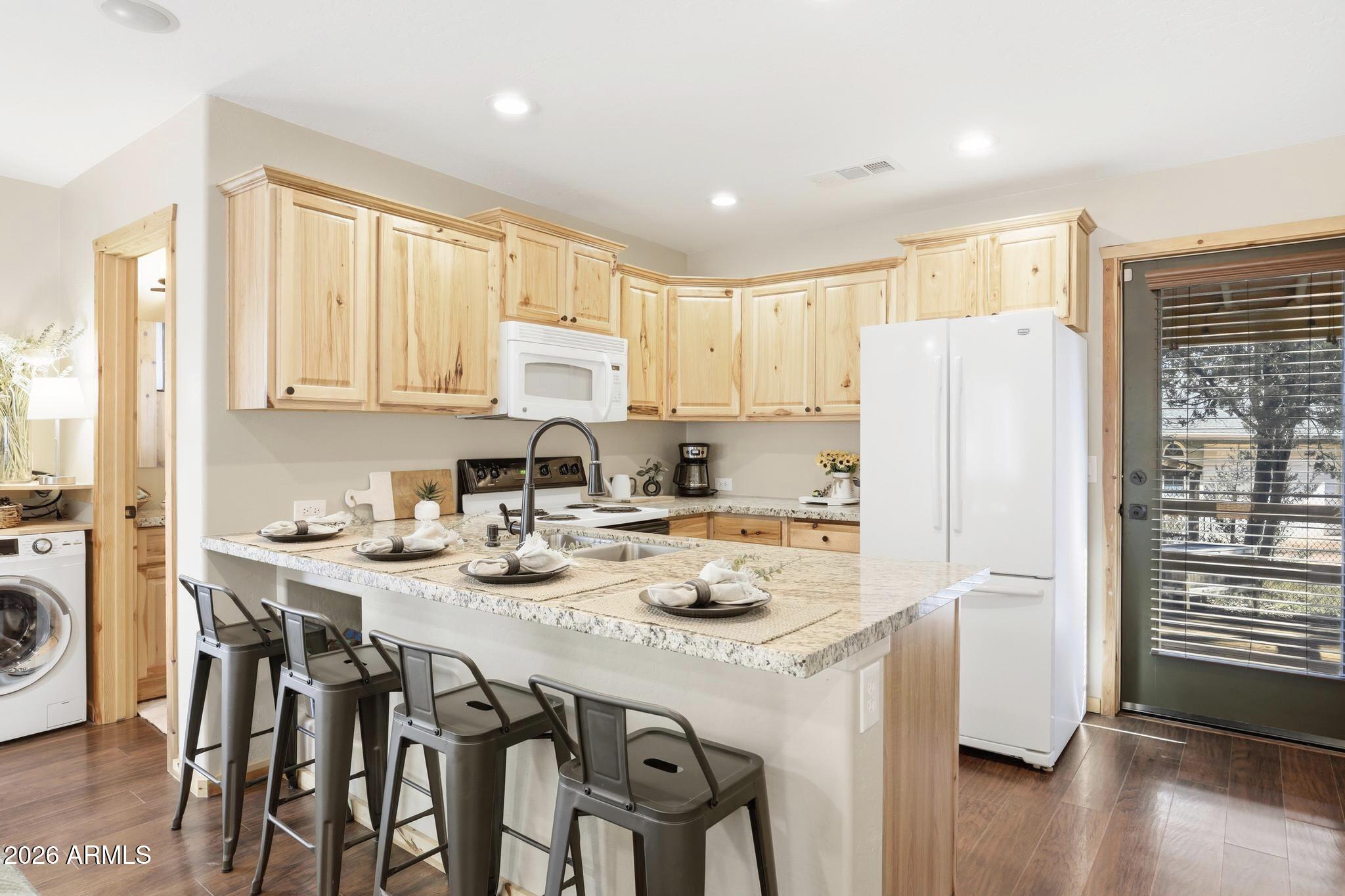 4023 Pine Road Pine, AZ 85544 - Photo 10 of 22 a kitchen with a refrigerator a stove a sink dishwasher and white cabinets with wooden floor