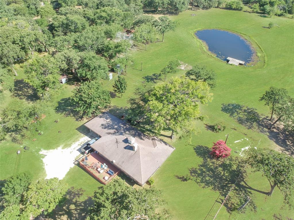 1001 Sandy Ridge Road Scurry, TX 75158 - Photo 5 of 35 Expansive grounds featuring a private pond with a small dock, mature trees, and a sprawling residence with a large outdoor deck