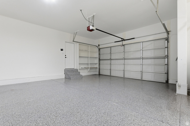 702 Alpine Highway Alpine, UT 84004 - Photo 74 of 83 Spacious garage featuring a durable epoxy-coated floor, automatic garage door opener, built-in shelving, and a service door for interior access
