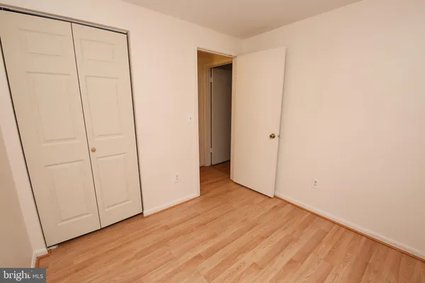 a view of an empty room with closet and wooden floor