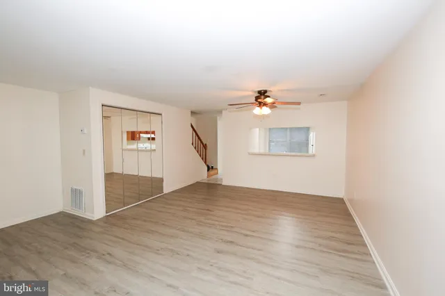 an empty room with wooden floor cabinet and windows