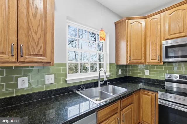 a kitchen with granite countertop a sink a stove and cabinets